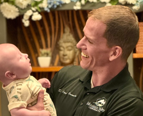 Dr. Joe Heinecke, DC holding an infant after an adjustment.