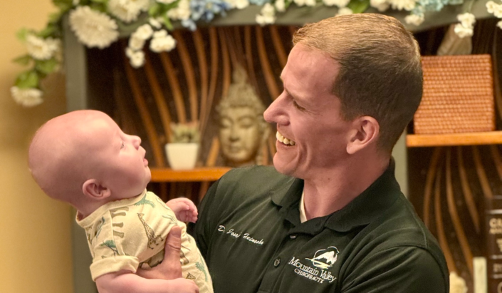 Why Kids and Infants Need Chiropractic Too featuring Dr Joe holding a happy infant