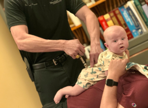 Dr. Joe Heinecke, DC adjusting an infant's lower back with an activator.