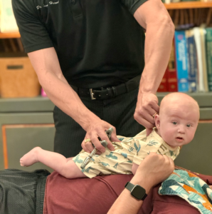 Dr. Joe Heinecke, DC checking an infant's spine for subluxations.