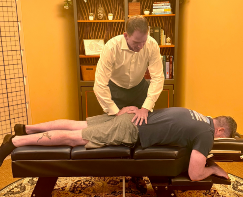 Dr. Joe Heinecke, DC adjusting a male patient's lower back.