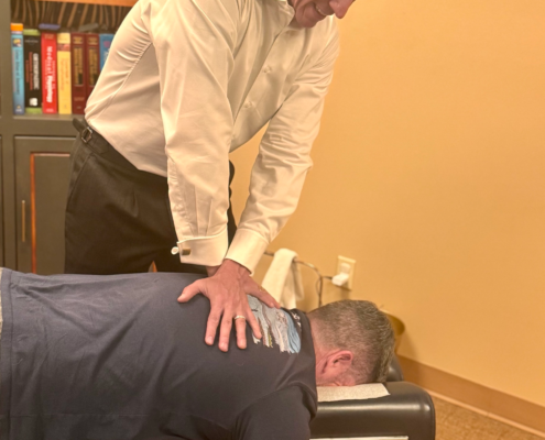 Dr. Joe Heinecke, DC adjusting a male patient's upper back.