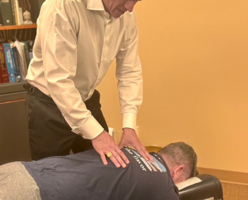 Dr. Joe Heinecke, DC performing a spinal analysis on a male patient.