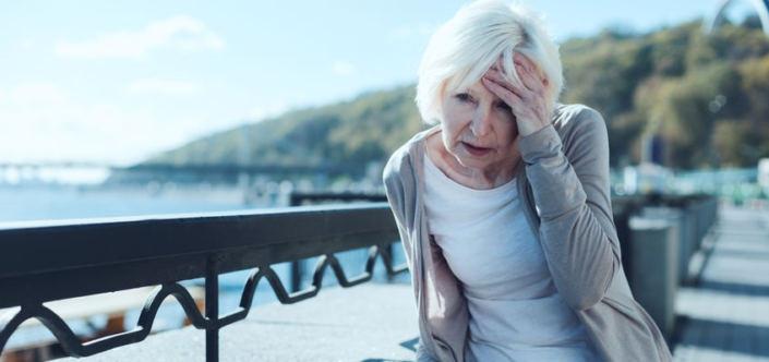 older woman outdoors holding her head seeking headache pain relief