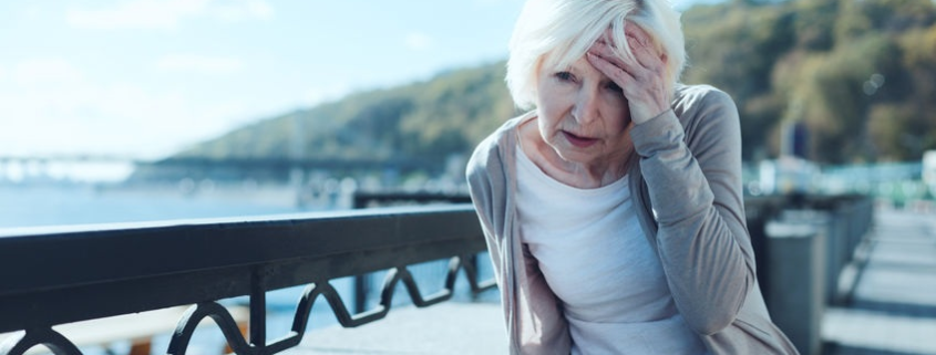 older woman outdoors holding her head seeking headache pain relief