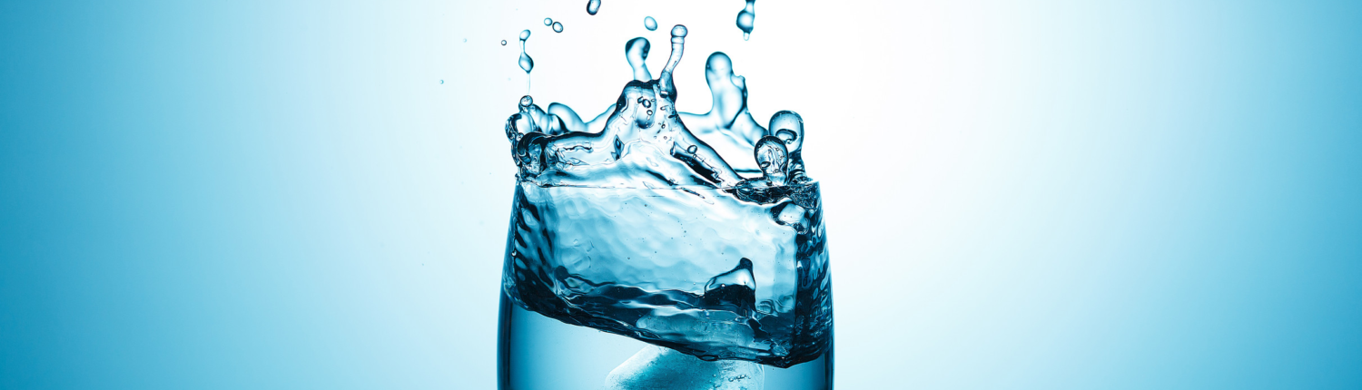 Glass of water splashing upwards.