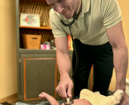 Dr. Joe Heinecke, D.C. is checking a newborn's heart rate.
