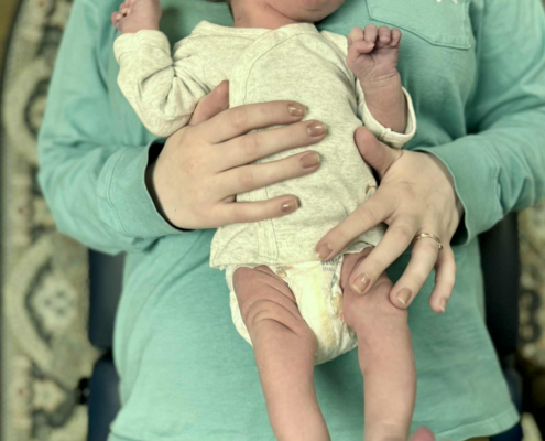 Dr. Joe Heinecke, D.C. is seen analyzing a newborn patient's skull bones.