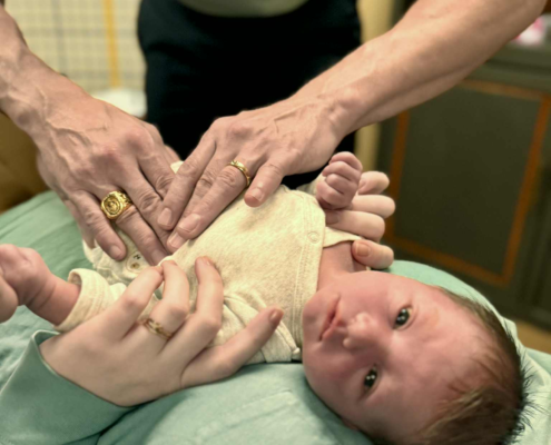Dr. Joe Heinecke, D.C. is seen adjusting a newborn baby during his first appointment.