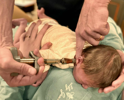 Dr. Joe Heinecke, D.C. is seen adjusting the atlas bone of an infant.
