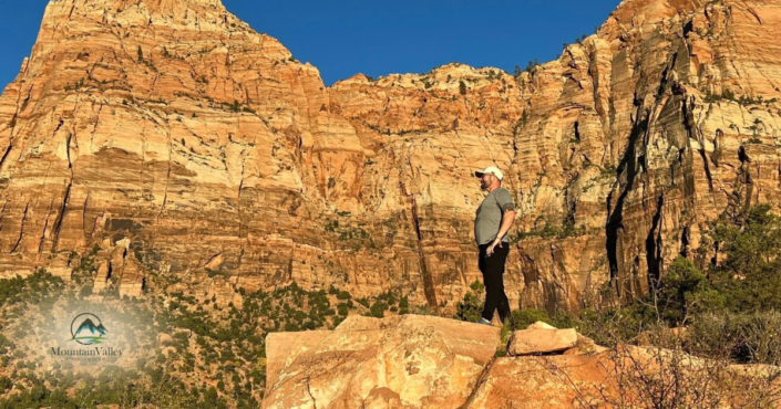 Hiker standing among red rock cliffs representing an active lifestyle and weather-related stiffness